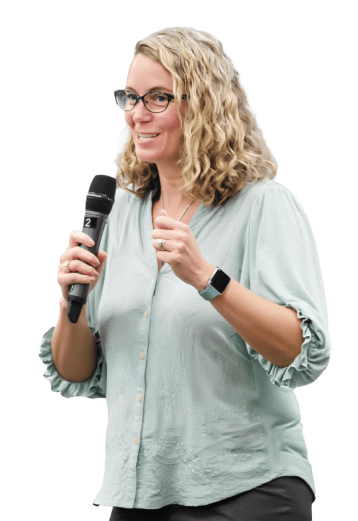 A woman with curly blonde hair speaking into a microphone.