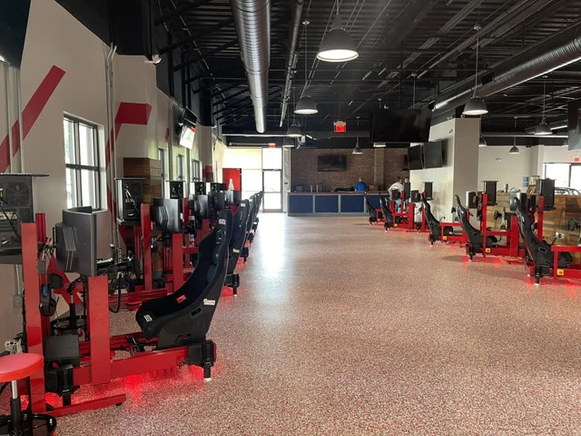 Empty gym with red and black workout machines and a large open space.