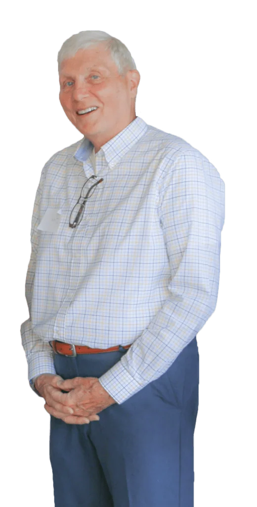 Older man with white hair smiling, wearing a checkered shirt and glasses.