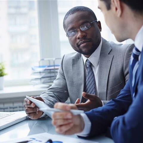 Image of two young businessmen interacting at meeting in office