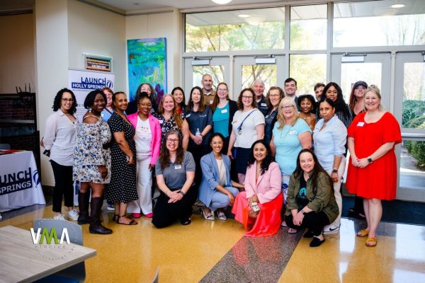 Group of diverse women gathered in a lobby for a photo.